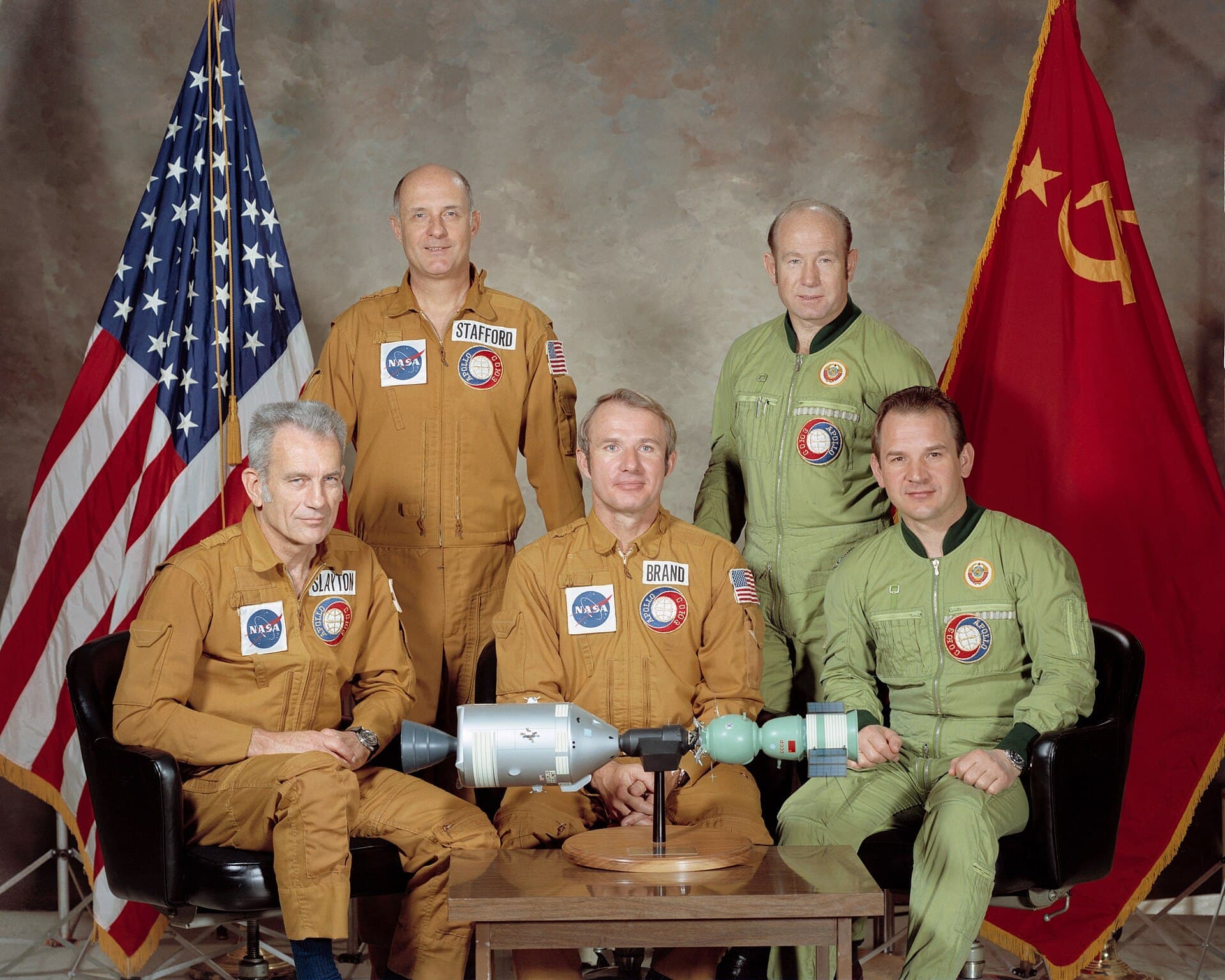 The five Apollo–Soyuz crew members photographed together: three American astronauts and two Soviet cosmonauts.