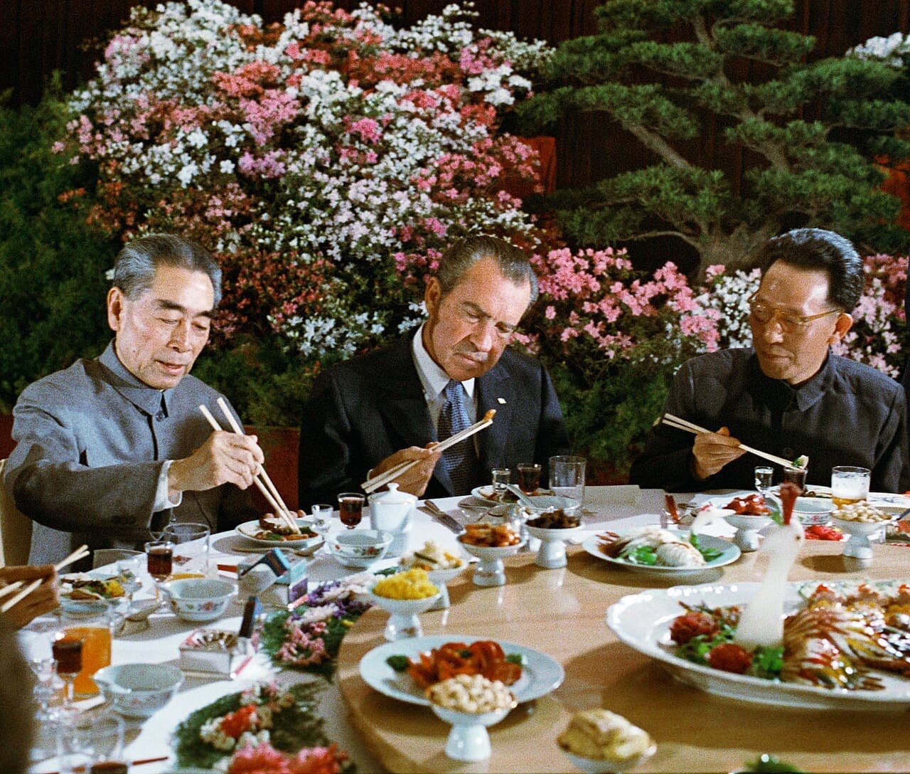 Richard Nixon eating with chopsticks at a banquet beside Chinese premier Zhou Enlai.